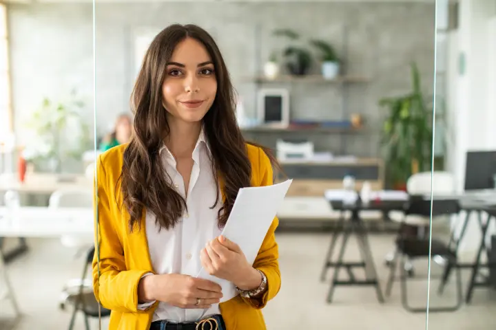 Smiling employee holding her course plan in a bright office